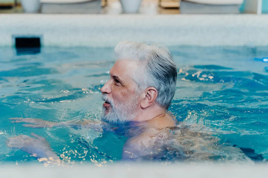 Seniorenman zwemt in helder binnenzwembad, ontspanning wateractiviteiten wellness