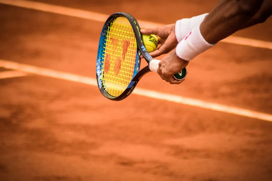 Close-up van tennisser met racket en bal op een gravel tennisbaan, sportwedstrijd