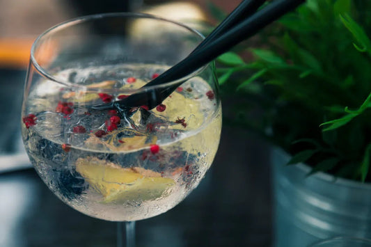 Gin tonic met ijs, citroen en roze peperbessen in een glas, frisse cocktail op tafel